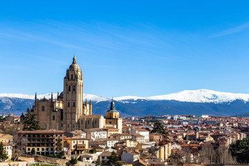 Obraz premium Segovia, Spain – View from Juan II tower in Winter time of the Alcazar of the old town of Segovia and the Cathedral with the snow capped Sierra de Guadarrama behind