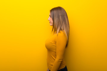 Fototapeta premium Young woman on yellow background in lateral position