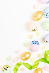 Festive Happy Easter background with decorated eggs, flowers, candy and ribbons in pastel colors on white. Copy space