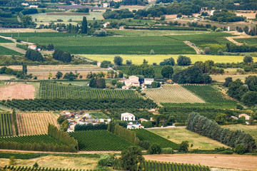 Fototapeta na wymiar Agricultural panoramic rural landscape of countryside in Southern France, Provence. Fields of geometrical shapes, village houses, all green and yellow. Travel France.