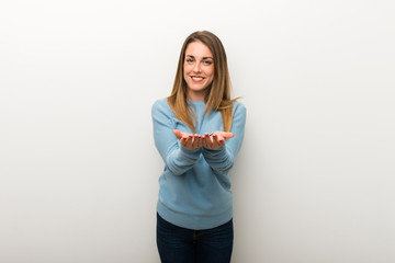Blonde woman on isolated white background holding copyspace imaginary on the palm to insert an ad