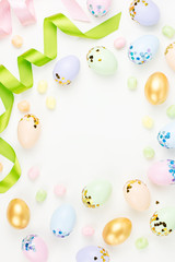 Fototapeta na wymiar Festive Happy Easter background with decorated eggs, flowers, candy and ribbons in pastel colors on white. Copy space
