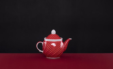 red ceramic teapot isolated on black background