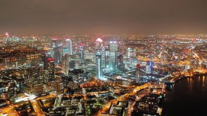 Aerial drone night shot from iconic Canary Wharf skyscrapers business area, Isle of Dogs, London,...