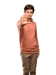 Teenager man with sweatshirt making stop gesture denying a situation that thinks wrong over...