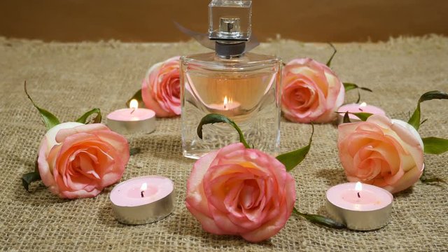 perfume in bottle, burning candles and pink roses, health spa setting
