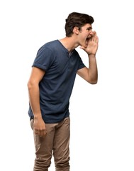 Teenager man shouting with mouth wide open to the lateral over isolated white background