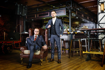Two successful stylish business partners in a pub. Two men in suits in the exclusive nightclub