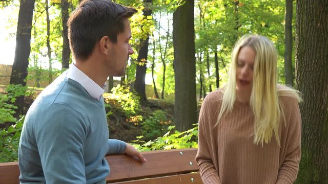 A couple argues on a bench in a park on a sunny day - closeup