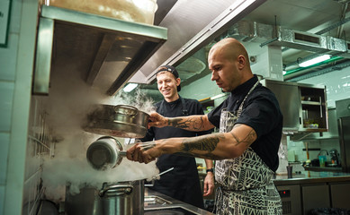 Culinary school. Handsome and confident chef teaching how to cook his two assistants in a...