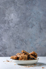 Homemade energy oats granola bars with dried fruits and nuts whole and broken in ceramic plate on grey table. Healthy snack.