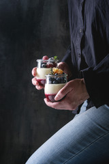Woman in black shirt holding in hands homemade classic dessert Panna cotta with raspberry and...