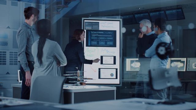 Engineers Meeting in Technology Research Laboratory: Female Engineer Leads Presentation Writes on Interactive Digital Whiteboard, Shows Machine Blueprint, Neural Network while Colleagues Listening
