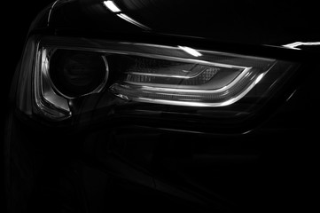 Car headlight on black background. Exterior detail.