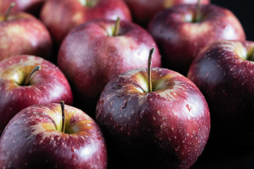 fragrant red apples lie in a row on a dark background