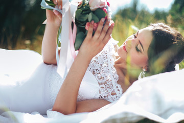 portrait of a beautiful happy bride against a green meadow and forest. The bride posing with a bouquet in her hands