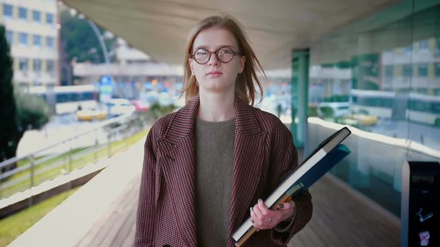 Young Attractive Professional Businesswoman In Glases Walking Confident Towards Camera Holding Documents In Her Hands Outside Trendy Modern Office Building