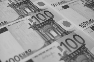 several banknotes of 100 euros close-up, monochrome.