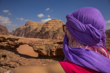 travel girl in Arabic hat back to camera enjoy by Wadi Rum Jordanian desert rocky scenery landscape