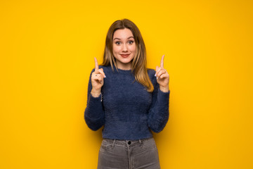 Teenager girl over yellow wall pointing with the index finger a great idea