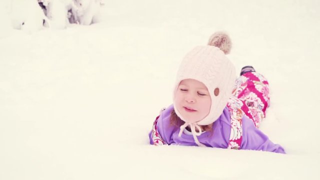 Slow motion. Little girl in pink hat playing in snow.