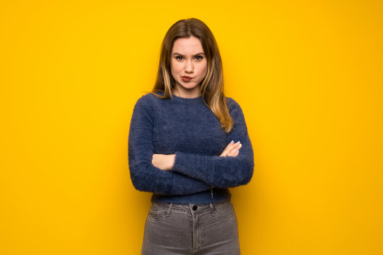 Teenager girl over yellow wall feeling upset