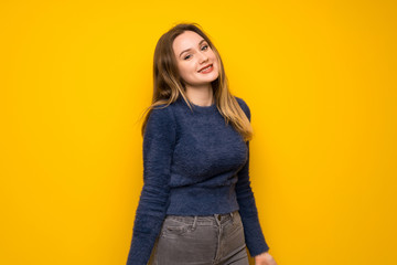 Teenager girl over yellow wall smiling