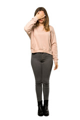 A full-length shot of a Teenager girl with pink sweater covering eyes by hands. Do not want to see something over isolated white background