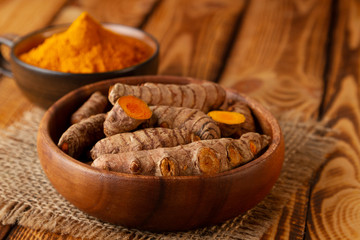 Turmeric roots and powder on wooden background. Selective focus on turmeric roots