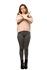 A full-length shot of a Teenager girl with pink sweater making NO gesture over isolated white background