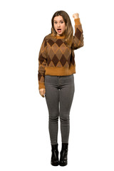 A full-length shot of a Teenager girl with brown sweater celebrating a victory in winner position over isolated white background