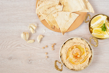 Homemade hummus with olive oil on a light background. Arabic bread on a wooden board