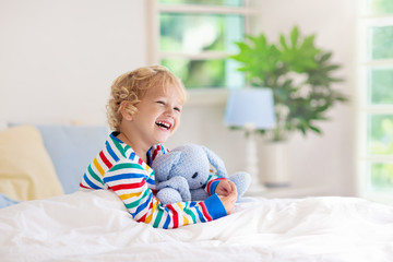 Child playing in bed. Kids room. Baby boy at home.