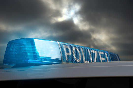 Polizeiauto mit Blaulicht vor grauem Himmel