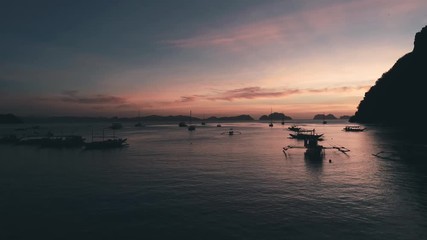 Aerial view of boats and yachts in the tropical bay on the sunset. El Nido, Palawan, Philippines. Marine tropical sunset over the sea. Travel concept.