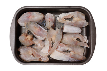 Fish cut by pieces on a metal baking sheet and prepared for roasting. Isolated on a white background