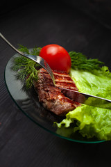 Tasty beef steak with green salad and tomato on the plate
