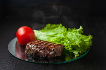 Juicy hot beef steak on dish with green salad and tomato
