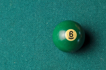 Old billiard ball number 6 green color on green billiard table, copy space
