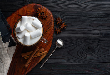 coffee with milk and marshmallow with cinnamon and anise on wooden background top view