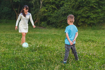 mother play with son in ball at green field.