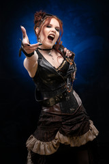 Beautiful redhead cosplay girl wearing a Victorian-style steampunk costume with a big breast in a deep neckline shouts and holds out her hand on a black and blue background
