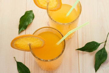 two glasses of fresh orange juice and a slice of orange