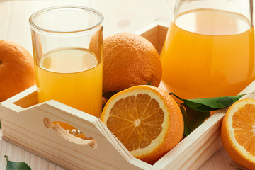 a glass of orange juice and orange fruit in a wooden box