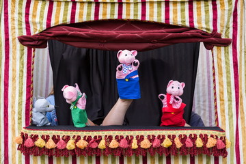 Children reenacting the story of the three little pigs and the big bad wolf with hand puppets in...