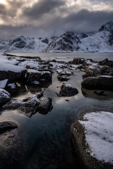 Reflection in water between the rocks at Vareid Coast on the Lofoten Islands in Norway in winter