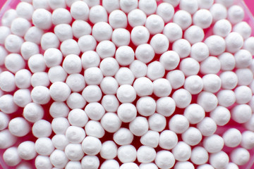 Closeup view from above on round pack of cotton buds on pink background