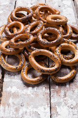 Photo of delicious bagels sprinkled with poppy seeds. Light wooden background