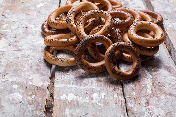 Photo of delicious bagels sprinkled with poppy seeds. Light wooden background