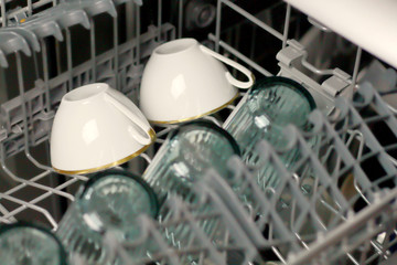 Dishwasher with glass cups and white porcelain cups washed dishes in a dishwasher 